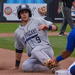 Austin Nola, in a gray New Orleans Zephyrs jersey, sliding feet first into a base