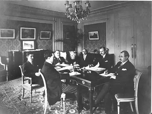 Azerbaijani delegation in Paris at the Claridge Hotel during the Paris Peace Conference, 1919. The tricolor flag of the ADR is visible in the background, on the chest of drawers.
