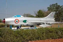 A color photograph of a metallic silver-colored aircraft numbered B784 on display in an open space