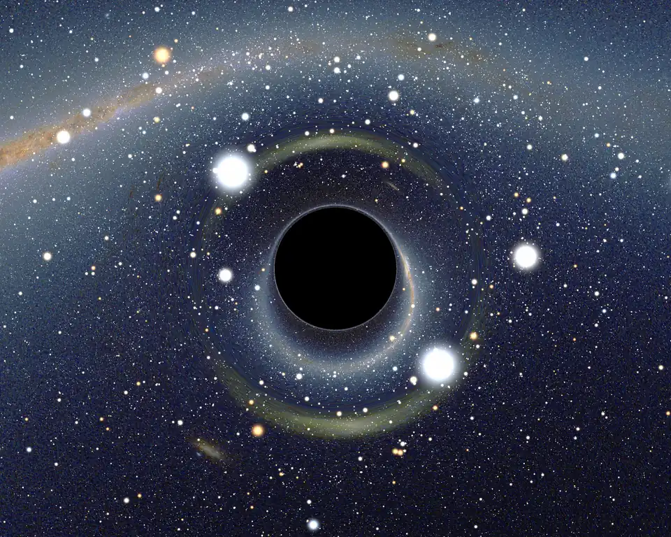 A black circle, center, surrounded by three bright white blobs of light and the orange-colored Milky Way distorted into an ark around it. The background is a starry sky with a second image of the Milky Way, not warped, visible in the top left corner.