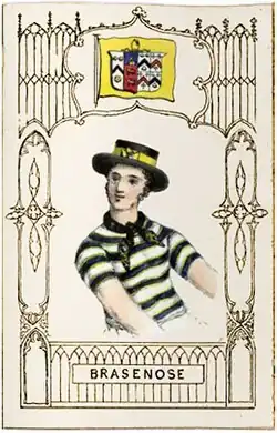 A man wearing a purple and yellow neckerchief and jersey, and a black and yellow hat, under flag showing a complicated shield on a yellow background