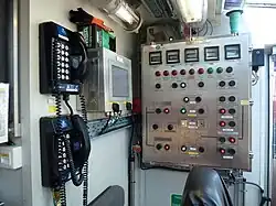 A blowout preventer (BOP) control unit located in a driller's cabin, showing switches, gauges, indicator lights and communication systems used for monitoring and controlling well pressure during drilling operations.