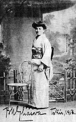 A white woman standing, wearing a kimono and a bouffant hairstyle