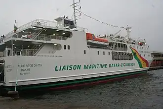 A ferry docked in harbor on an overcast day. It is designated the "Aline Sitoe Diatta".