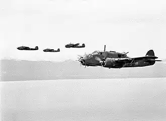 Four twin-engined military aircraft in low-level flight over the ocean