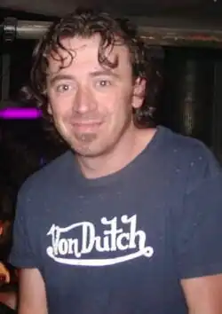 Benny Benassi smiling towards the camera. His curly hair falls on his face