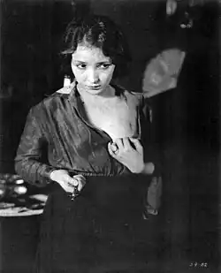 Young woman clutching her open blouse while holding a syringe with a troubled, downward gaze