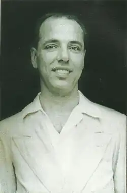 Black and white photographic portrait of a young man in a white open-neck shirt