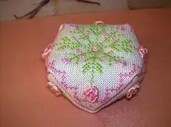 cross stitched biscornu with satin ribbons