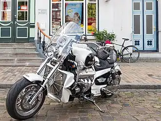 Large silver-colored solo motorcycle with protruding engine and chrome-plated exhaust