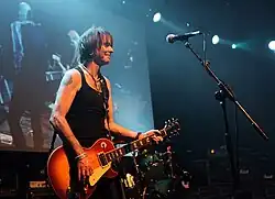 Robertson onstage holding his guitar and smiling
