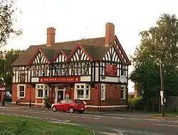 Photo of a the pub, a mock tudor and brick building by the main road.