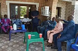 Eight men gathered for bride price payment in Nigeria. One man is standing and counting out cash.