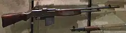 Early-pattern M1918 Browning Automatic Rifle shown in profile, with a long barrel, fixed bipod, and wooden stock.