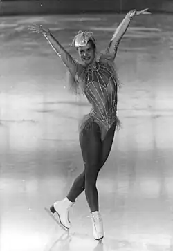 Witt's costume is a leotard with a faux low cut and bright vertical stripes. A few feathers cover her hips at the sides