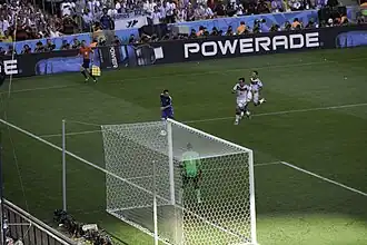 View from behind the goal of Messi with the ball, while two German defenders chase him and the goalkeeper stands guard