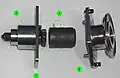 A partially disassembled CBM Powered Bolt, showing both ends of the shaft (1), the lower housing (2) that nestles into the ACBM ring, the drive sleeve (3) and its spline interface with the shaft, and the upper housing (4). The upper housing and drive sleeve can be removed without demating the vestibule to install a spline lock under an IVA seal "butter dish". The spline lock prevents the bolt from backing out.[6][119]