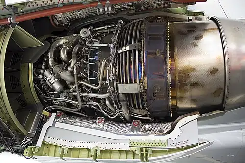 This view shows the way turbine blade tip clearance is controlled actively (passive control is by material selection and internal air system cooling) using cooling-air tubes (for low pressure turbine blade tip to shroud clearance control) which circle the iridescent turbine casing on a CFM International CFM56. Cooling air manifold (smooth flat surface), to left of LPTCC tubes, for high pressure turbine blade tip clearance control.[124] Active control comes from activation of valves which supply cooling air to the tubes at appropriate flight conditions.