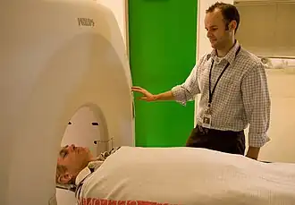 A man is lying on his back, about to go inside a cylindrical chamber.