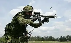 Canadian soldier firing a C7A2 rifle fitted with a C79A2 optical sight.