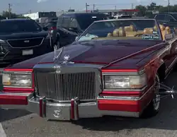 Red Cadillac convertible with front grill and elbows and tan leather seats