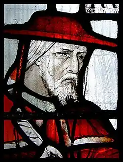 A stained glass portrait of Cardinal John Morton in red clothing.