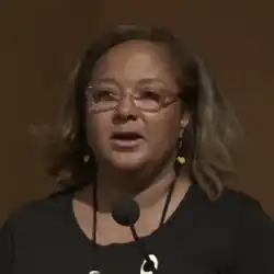 Headshot of Williams wearing glasses over a brown background