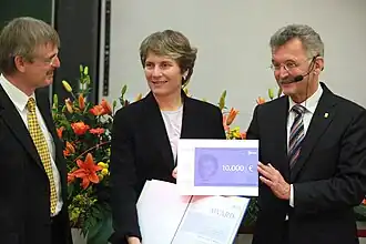 Carolyn Bertozzi in front of a floral piece receiving an award