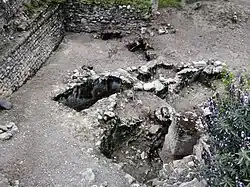 Group of filled tombs next to a ruined wall