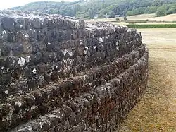 Color photograph of a curved wall with successive recessed courses forming projections.