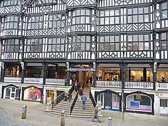There are shops on the street level with wide steps leading to the first floor where there on more shops on the Rows. Above this are 2+ storeys in black-and-white architecture.