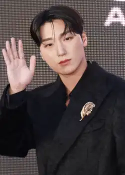 San wearing a black coat and waving