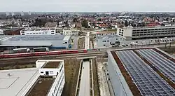 A picture of a paved walk- and cycle path crossing below several train tracks.