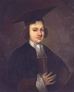 Half length and dark portrait of a serious and slightly plump man wearing a black academic gown with white collar, ruffled cuff, and a large mortarboard.