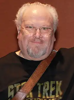 2015 headshot of Colin Baker with a beard and glasses