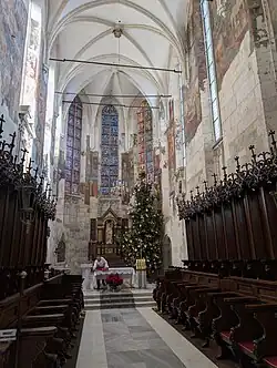 The interior of a 14th century church, showing a high ceiling and paintings on the walls.