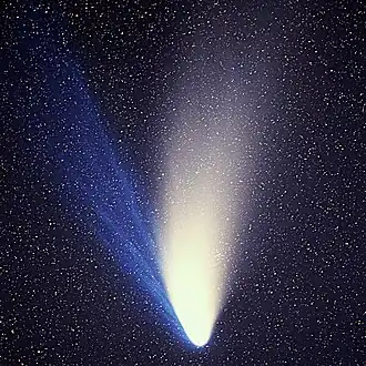 At lower left, a white coma stands out against a black background. Nebulous material streams away to the top and left, slowly fading with distance. (from Solar System)
