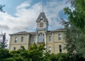 Front view of the building's exterior showing all three floors and the dense landscaping surrounding it