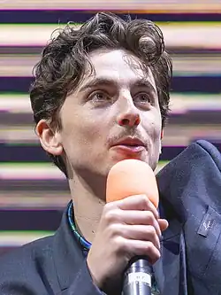 A caucasian male with dark hair speaks into a microphone