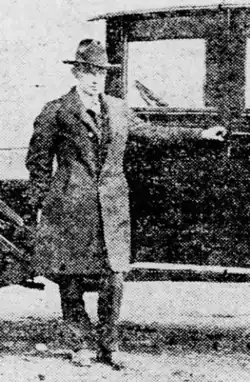 Black and white photo of Gaard in a suit in front of an old sedan