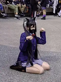 A young woman wearing cat ears and a school girl outfit posing for a photograph.