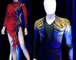 The costumes are displayed on mannequins and feature numerous sequined feather decorations