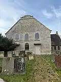 A stone church with chancel and a small bell-cot