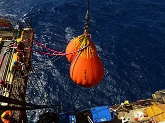 Offshore support vessel using a crane to lift heavy equipment at sea, illustrating logistics and construction work around oil platforms.