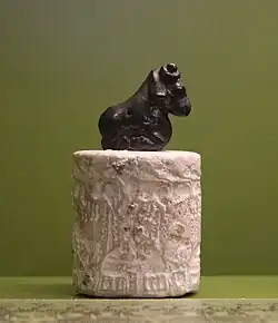 Cylinder seal representing cattle and reed huts, surmounted by a crouching ram in copper alloy. Ashmolean Museum.