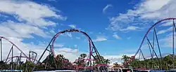 A train twisting through DC Rivals HyperCoaster's non-inverting loop, seen from the car park