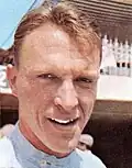 Dan Gurney in racing overalls smiling at the camera