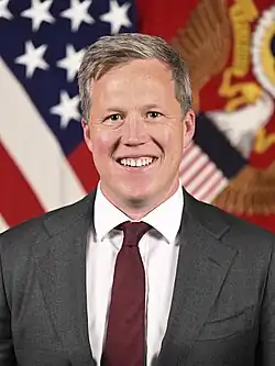 Head shot of Driscoll wearing a suit and smiling
