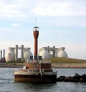 Deer Island Light in 2009, with Deer Island Waste Water Treatment Plant digesters in the background.