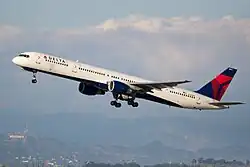 A white and blue 757 takes off with the Hollywood sign in the background